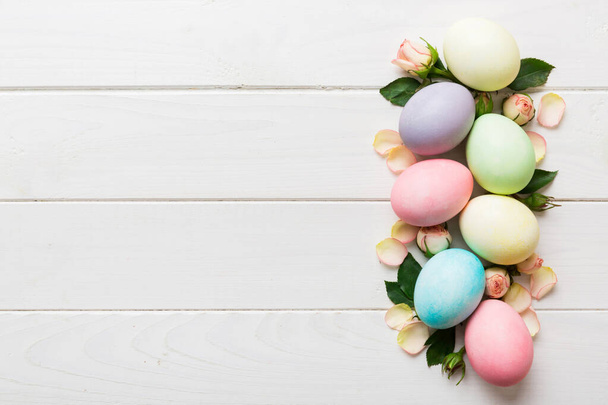 Boldog Húsvétot! Húsvéti tojás a színes asztalon sárga rózsákkal. Természetes festett színes tojás háttér felülnézet másolási hely. - Fotó, kép
