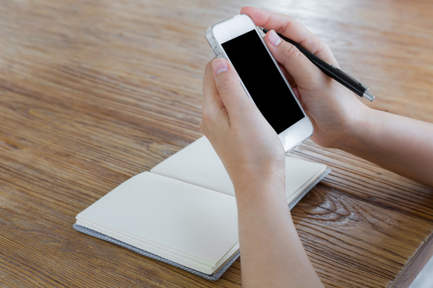 Woman using smart phone on the table with book - Foto, Imagen