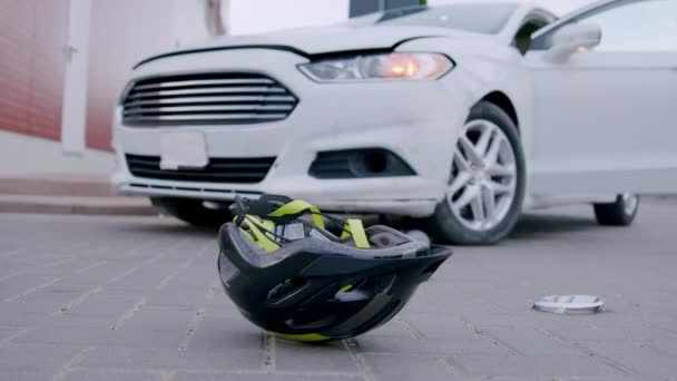 Autonehoda s cyklistou. helma v popředí a auto sražené cyklistou v pozadí, zobrazující následky srážky - Záběry, video