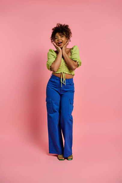 Элегантная афроамериканка позирует в стильной одежде на ярком розовом фоне. - Фото, изображение