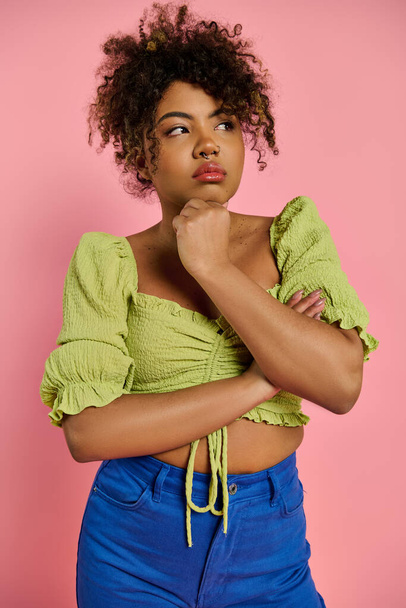 Eine schöne Afroamerikanerin, emotional und stilvoll, posiert in einem gelben Oberteil vor einem lebendigen Hintergrund. - Foto, Bild