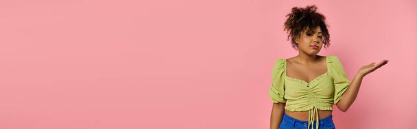 Африканська американка в стильному вбранні витончено позує на яскраву рожеву стіну. - Фото, зображення
