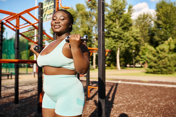 Afroamerikanerin in Sportbekleidung turnt selbstbewusst vor Fitnessgeräten. - Foto, Bild