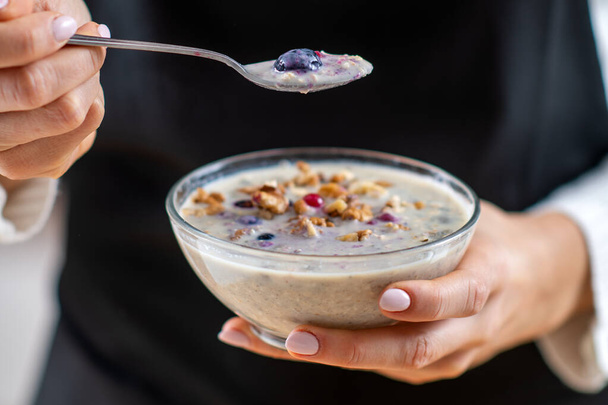 Woman holding Healthy bowl of oatmeal, rich in wholesome oats, creamy soy milk, and a delightful mix of crunchy nuts for a supercharged breakfast - Photo, Image