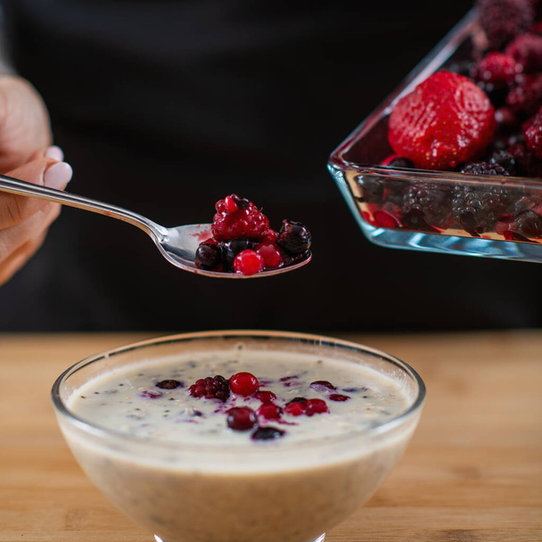 woman holding spoon full of berries and oatmeal, combining wholesome oats, creamy soy milk, and a medley of luscious berries for a vibrant and nutritious breakfast.  - Photo, Image