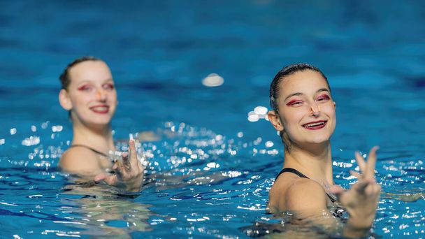 Pływanie synchroniczne jako dynamiczny duet przynosi płyn artystyczny do basenu, pełne wdzięku ruchy i zsynchronizowaną precyzję urzekają hipnotyzującym tańcem wodnym - Zdjęcie, obraz