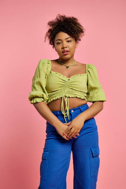 Stylish African American woman poses in yellow top and blue pants against a vibrant backdrop. - Photo, Image