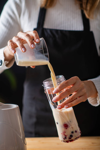 женщина Создание питательный коктейль с добротой соевого молока и ярких ягод для восхитительного оздоровительного лечения - Фото, изображение