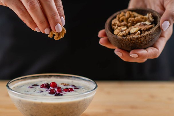 woman preparing Healthy bowl of oatmeal, rich in wholesome oats, creamy soy milk, and a delightful mix of crunchy nuts for a supercharged breakfast - Photo, Image