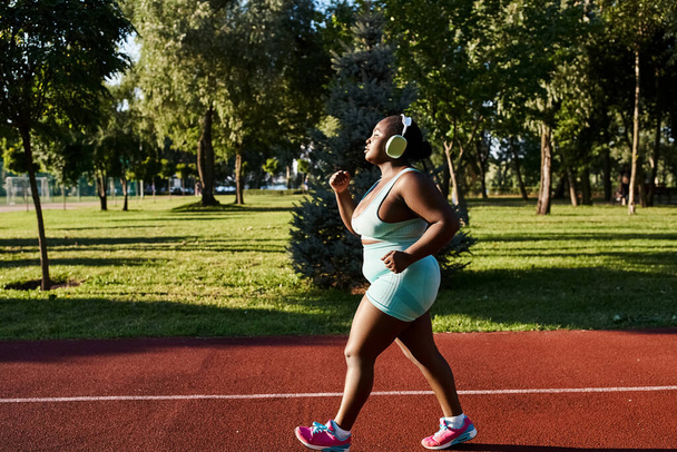 Afroamerykanka w stroju sportowym, świętująca swoje łuki, biegnie z wdziękiem po korcie tenisowym w plenerze. - Zdjęcie, obraz