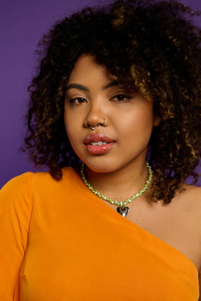 Piękna Afroamerykanka w pomarańczowym top i naszyjnik stanowi na tętniącym życiem tle. - Zdjęcie, obraz