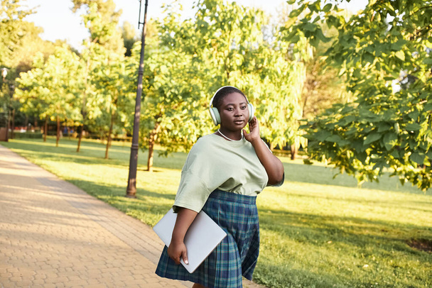 Plus size African American woman in casual attire striding along sidewalk - Photo, Image