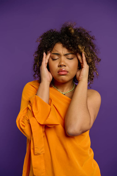 Emocionální Afroameričanka v oranžové košili drží hlavu v tísni. - Fotografie, Obrázek
