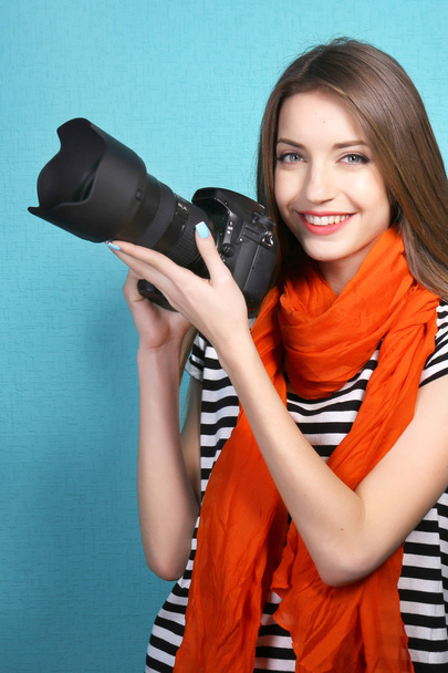 Young female photographer taking photos on blue background - 写真・画像