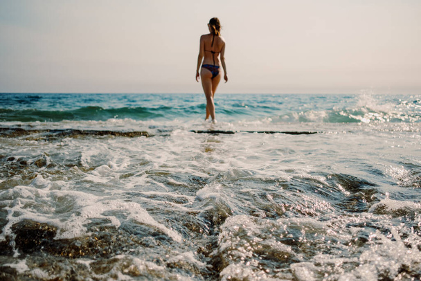 Yksinäinen uimari seisoo valmiina veden äärellä valmiina sukeltamaan kuohuvaan Välimereen. - Valokuva, kuva