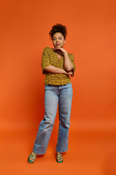 Stylish African American woman posing in front of a vibrant orange backdrop. - Photo, Image