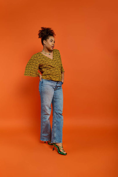 Stylish African American woman striking a pose against a vibrant orange background. - Фото, зображення