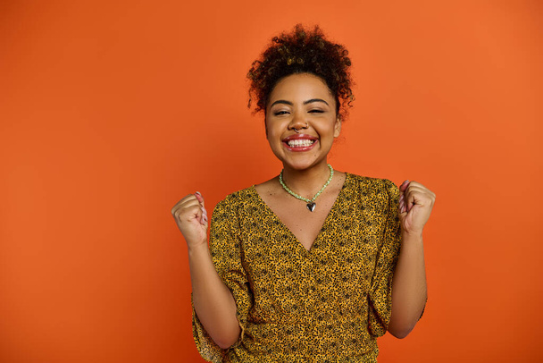Afroameričanka ve stylovém oblečení, zářivě se usmívající na živém pozadí. - Fotografie, Obrázek