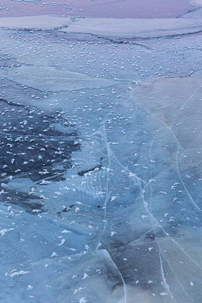 Красивые треснувшие ледяные узоры на поверхности замёрзшего озера зимой в Латве. Холодные пейзажи Северной Европы. - Фото, изображение