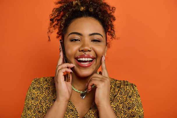 Красива афроамериканка в стильному вбранні посміхається під час розмови на мобільному телефоні. - Фото, зображення