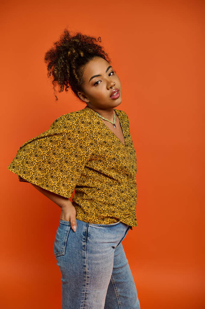 Елегантна афроамериканка позує в стильному вбранні проти яскравого помаранчевого фону. - Фото, зображення