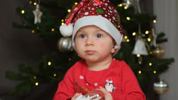 Portrét 11 měsíců staré dítě v Santa klobouk hrát s vánoční hračkou. - Záběry, video