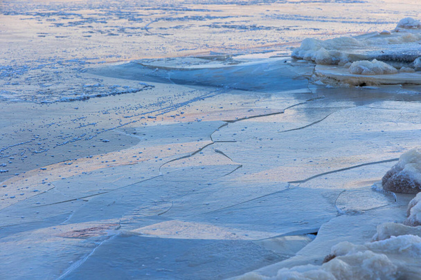 Прекрасні тріщини льоду на замерзлій поверхні озера взимку в Латвії. Холодні пейзажі Північної Європи. - Фото, зображення
