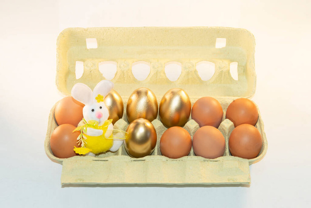 Karton papír tálca barna, arany tojást egy húsvéti nyuszi.Pack festett tojás.Ár emelkedés.Tojás doboz, Előkészítés. Fényképezőgépet használó FOTO CREATING - Fotó, kép