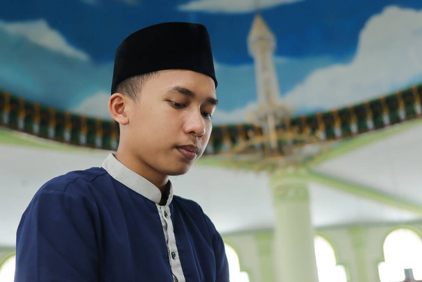Retrato de un hombre asiático religioso con camisa musulmana rezando y haciendo salat o sholat en la mezquita - Foto, Imagen
