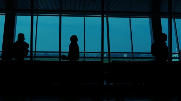 Against a windows warm glow, figures in motion of silhouettes of passengers at the Juanda Airport, Surabaya, Indonesia. - Footage, Video