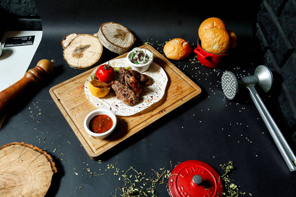Een houten snijplank met een heerlijk assortiment vers bereid vlees en groenten. - Foto, afbeelding