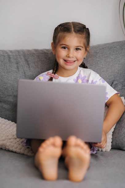 Retrato de una hermosa niña usando un artilugio inteligente. Chica de cinco años de edad abrir y utilizar el ordenador portátil. Foto de alta calidad - Foto, imagen