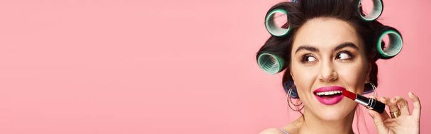 Woman with curlers holding lipstick. - Photo, Image