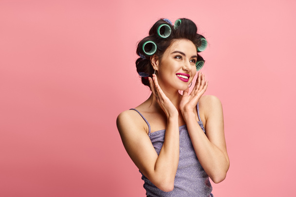 A vibrant backdrop frames an attractive woman with curlers in her hair posing confidently. - Photo, Image