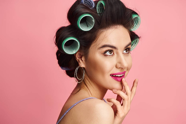 A stunning woman with curlers in her hair poses for the camera against a vibrant backdrop. - Photo, Image
