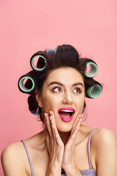 A woman with curlers in her hair poses against a vibrant backdrop. - Photo, Image