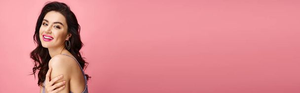 Una mujer impresionante posa frente a un telón de fondo rosa vivo. - Foto, imagen