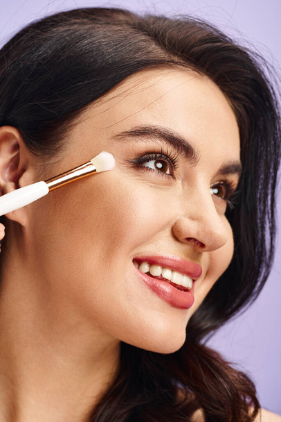 Una mujer que mejora su belleza natural mediante la aplicación de maquillaje con un cepillo. - Foto, imagen
