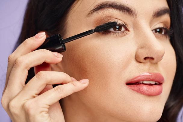 A woman with natural beauty delicately applying mascara to enhance her features. - Photo, Image