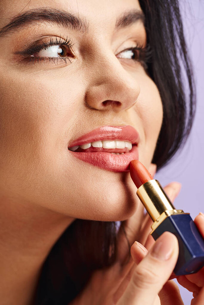 Een prachtige vrouw brengt sierlijk lippenstift aan op haar lippen. - Foto, afbeelding