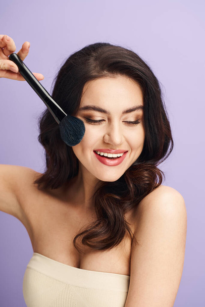 A charming woman creatively styling her face with a brush. - Photo, Image