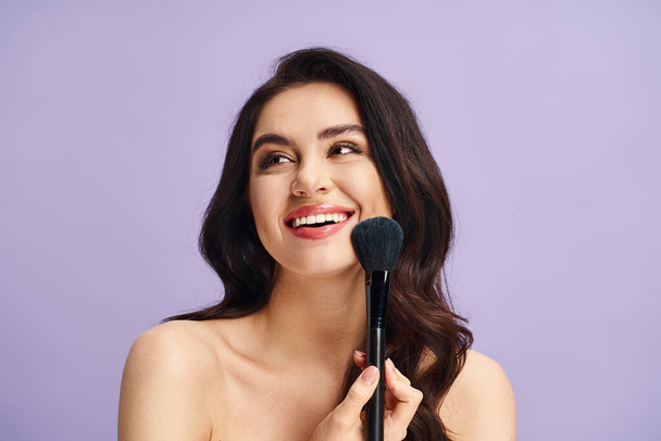 A woman with natural beauty delicately holds a makeup brush in her hand. - Photo, Image