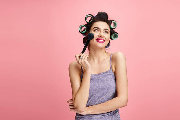 A woman with curlers in her hair holds a brush. - Photo, Image