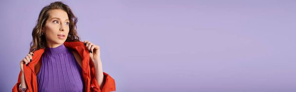 A stylish young woman wearing a purple shirt and a red jacket against a vibrant purple background. - Photo, Image
