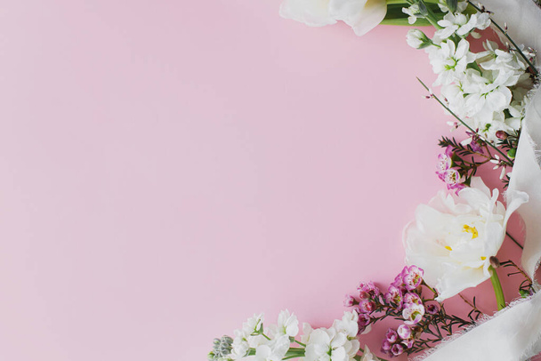 Šťastný Den matek a Den žen. Na růžovém pozadí ležely stylové bílé květy, prostor pro text. Krásné jemné tulipány a okraje jarních květin, šablona blahopřání. Květinový prapor - Fotografie, Obrázek