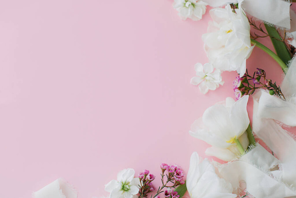Счастливого Дня Матери. Стильные цветы плоские лежали на розовом фоне с пространством для текста. Белые нежные тюльпаны и весенние цветы границы, шаблон поздравительной открытки. Цветочный баннер. С Днем женщин! - Фото, изображение
