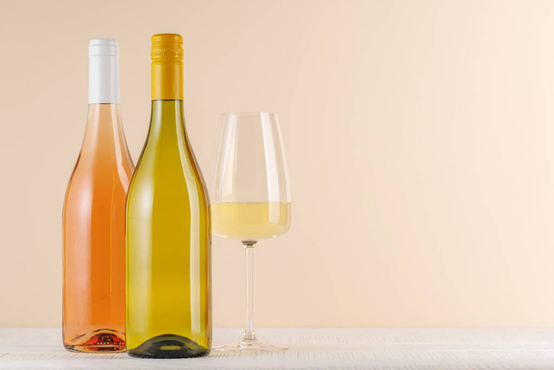 Rozen- en witte wijnflessen op tafel met kopieerruimte - Foto, afbeelding