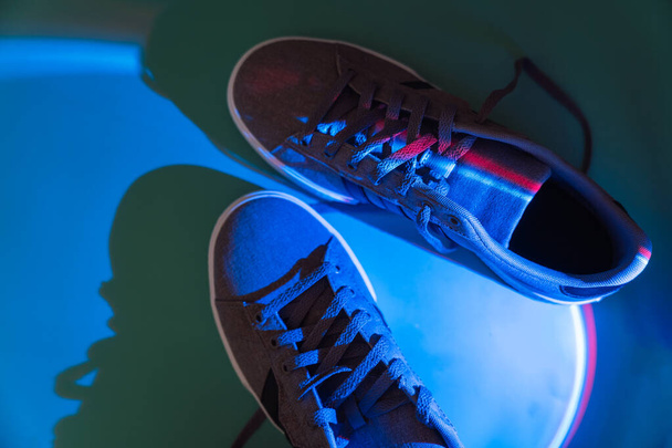 Тканевые кроссовки с резиновой подошвой под голубым светом. - Фото, изображение
