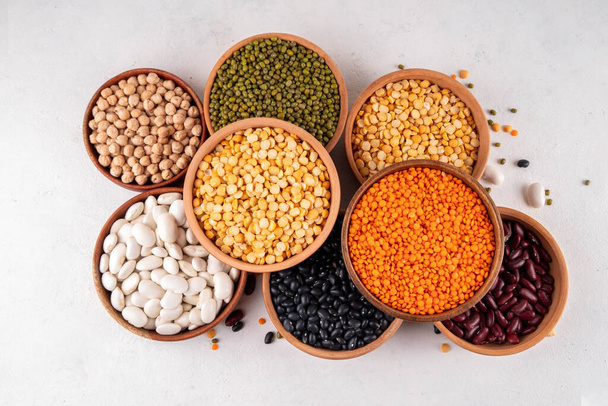 Various dried  beans, lentils, mung, chickpea, pea  assortment in wooden bowls. Legumes on white table top view. Vegan protein sources food, copy space - Photo, Image