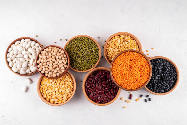 Various dried  beans, lentils, mung, chickpea, pea  assortment in wooden bowls. Legumes on white table top view. Vegan protein sources food, copy space - Photo, Image